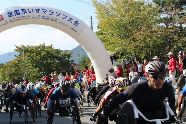 全国車いすマラソン大会と書かれたスタート地点を車いすのランナー達が走っている写真