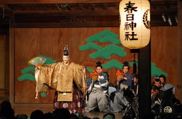 春日神社能楽殿にて小鼓の演奏に合わせて能の舞が行われている写真
