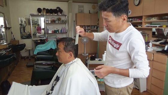 理容師がお客さんの髪をくしで整えている写真