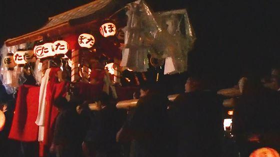 灯りのついた提灯が下げられている屋根付きの神輿を担いでいる写真