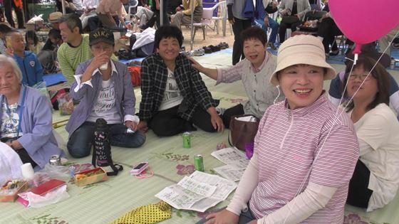 テントの中でゴザを敷いてお弁当を食べる人々の写真