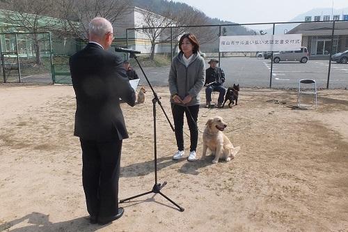 ゴールデンレトリバーを連れた女性を市長が表彰している写真