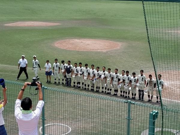 グランドの観客席の前に、篠山鳳鳴高校軟式野球部の選手が一列に並び帽子を取って立っている様子の写真