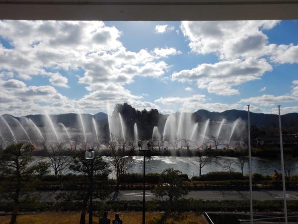 道路の向こうの池に向かって放水演習が行われている様子の写真