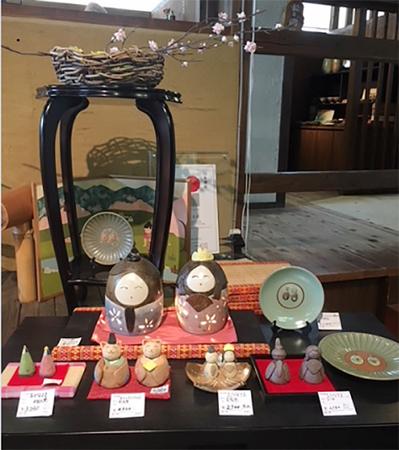 机の上に飾られた、様々なデザインの陶器のひな人形の写真