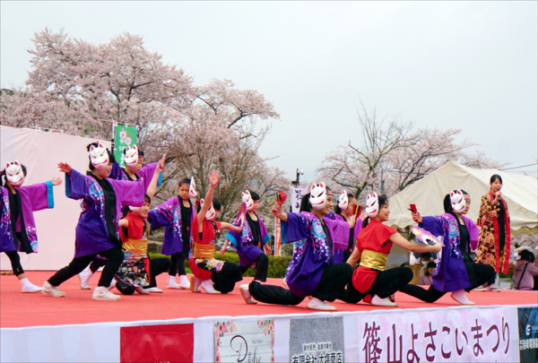 白狐のお面を顔の右横に付けステージ上でダンスをしている11人の子供たちの写真
