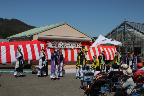 ステージの前で法被姿の出演者が片手を振り上げている写真