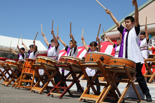 ステージで子供達が両手を振り上げ締太鼓を叩いている写真