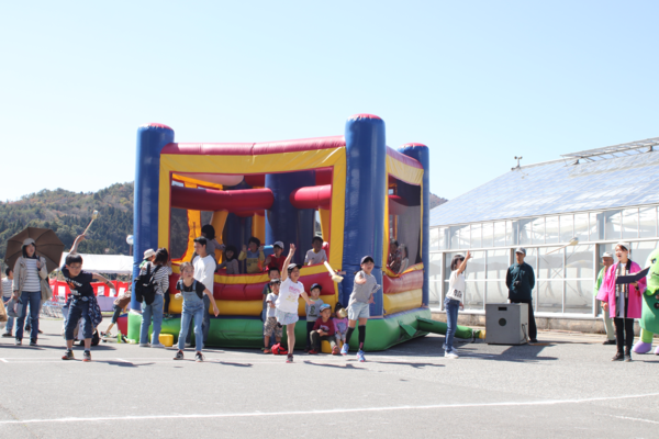 巨大ふわふわエアートランポリンの中で子供達がシャク投げを見ている写真