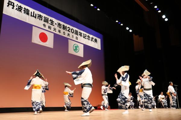 ステージ上で円になりよさこいを踊っている人達の写真