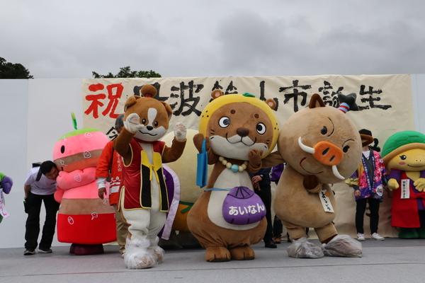 左からゆるキャラの「わんまるくん」（犬）、「なーしくん」（カワウソ）、「まるいの」がステージ中央でポーズを決めている写真