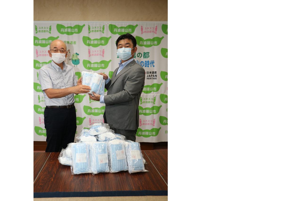 東洋技研の田畑社長と酒井市長がマスクをてにとっている