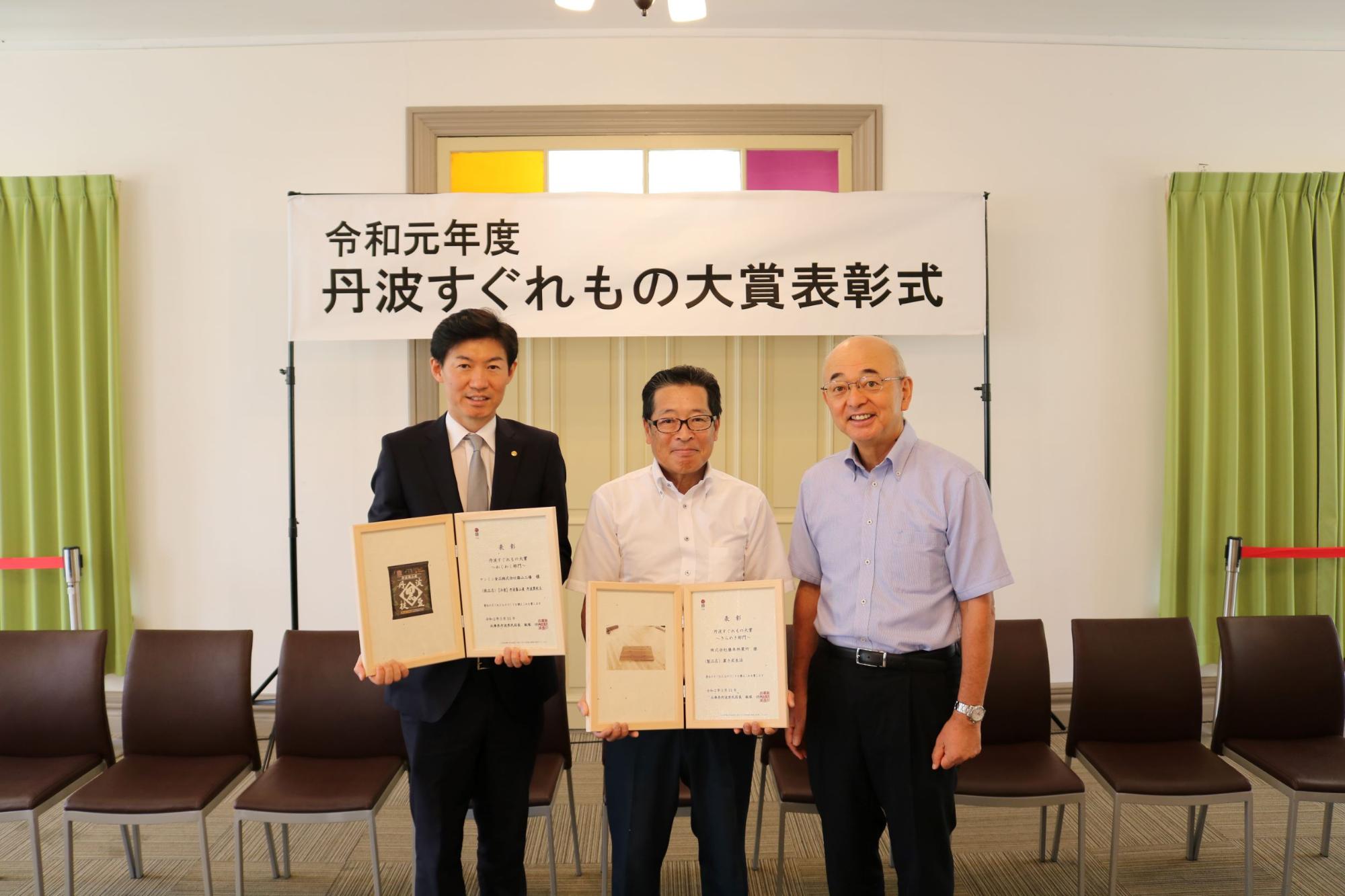 表彰状を手にしたケンミン食品高村社長、藤本林業所藤本社長、酒井社長の写真