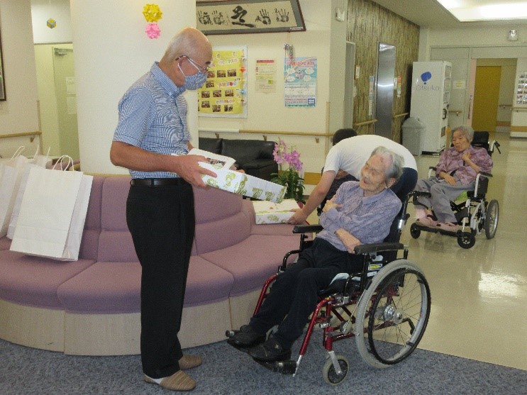 車いすに乗っておられる森本さんに、市長が記念品を贈呈している