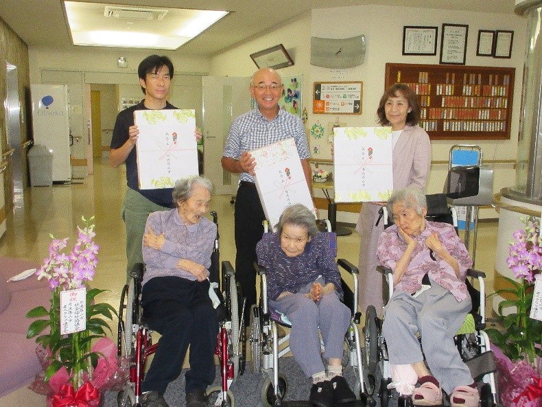 車いすにのっておられるご長寿の方3人と市長、市関係者で記念撮影