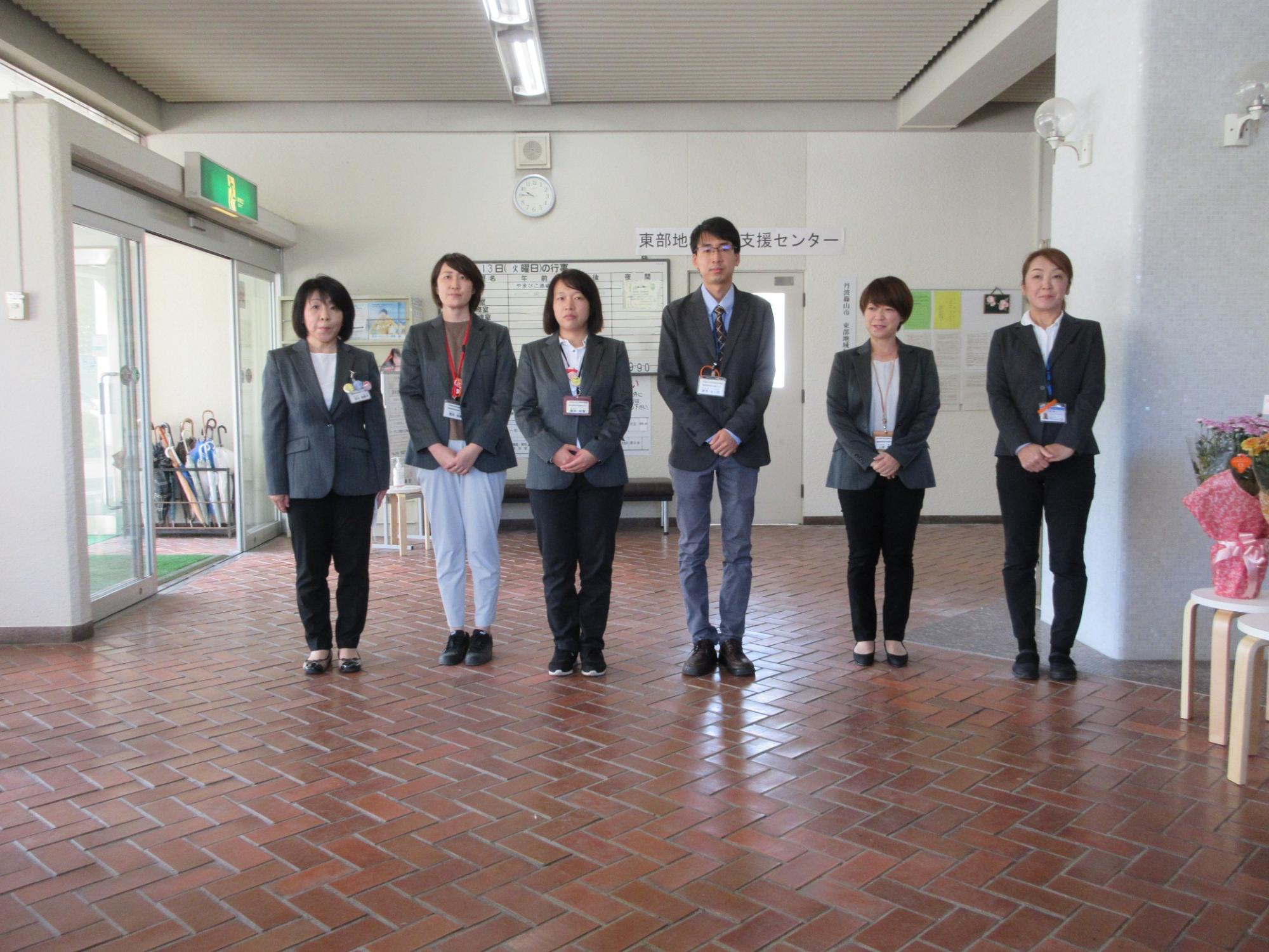 玄関ホールで職員6名が横に並んで立っている