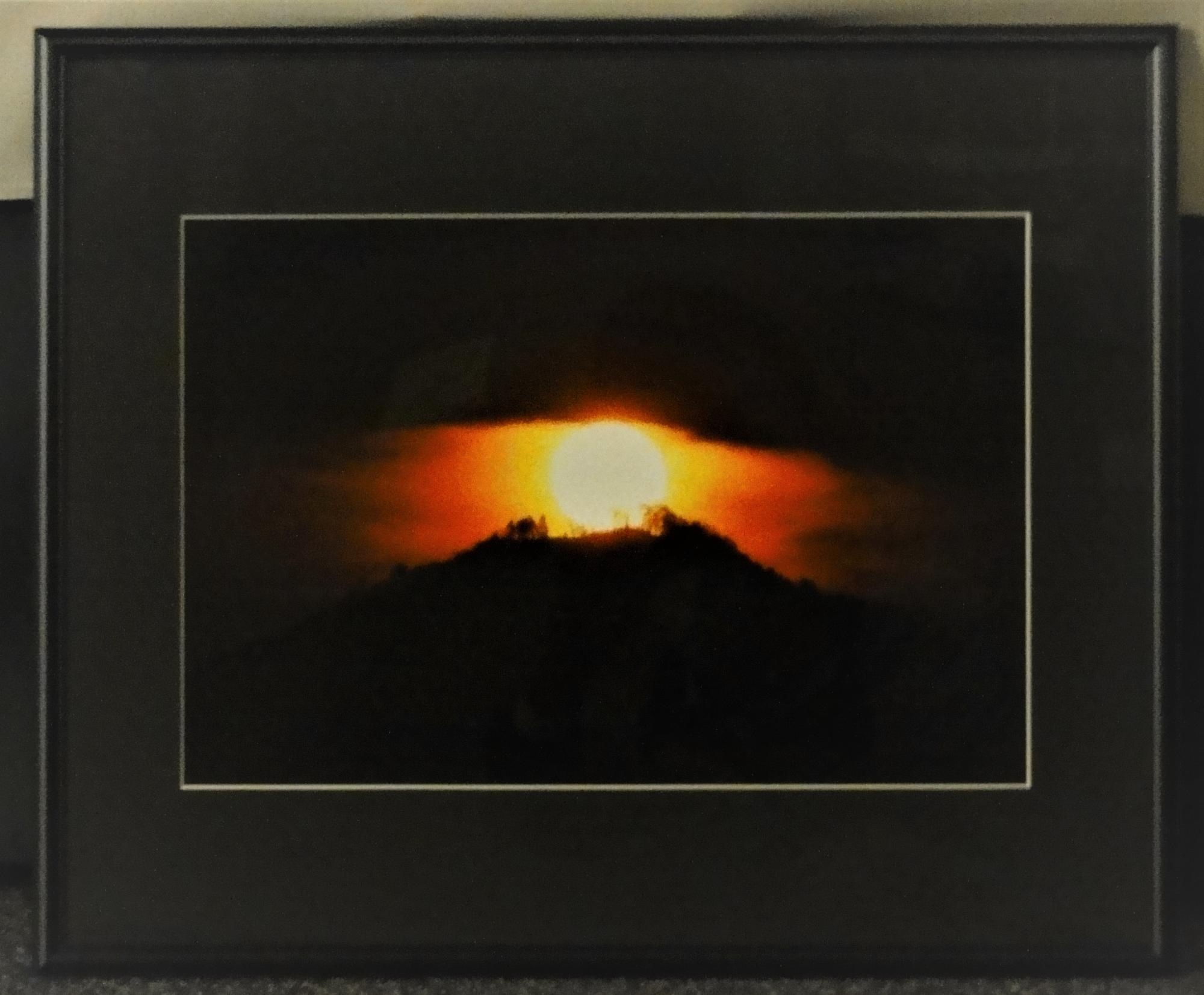 写真の作品。山の頂上に朝日がのぼってきたところを映している。