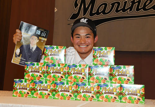 仮契約の会見での千葉ロッテのユニフォーム姿の中森投手。「パイの実」が並べられていて手には自信が表紙を飾った丹波篠山の広報紙を持っている。
