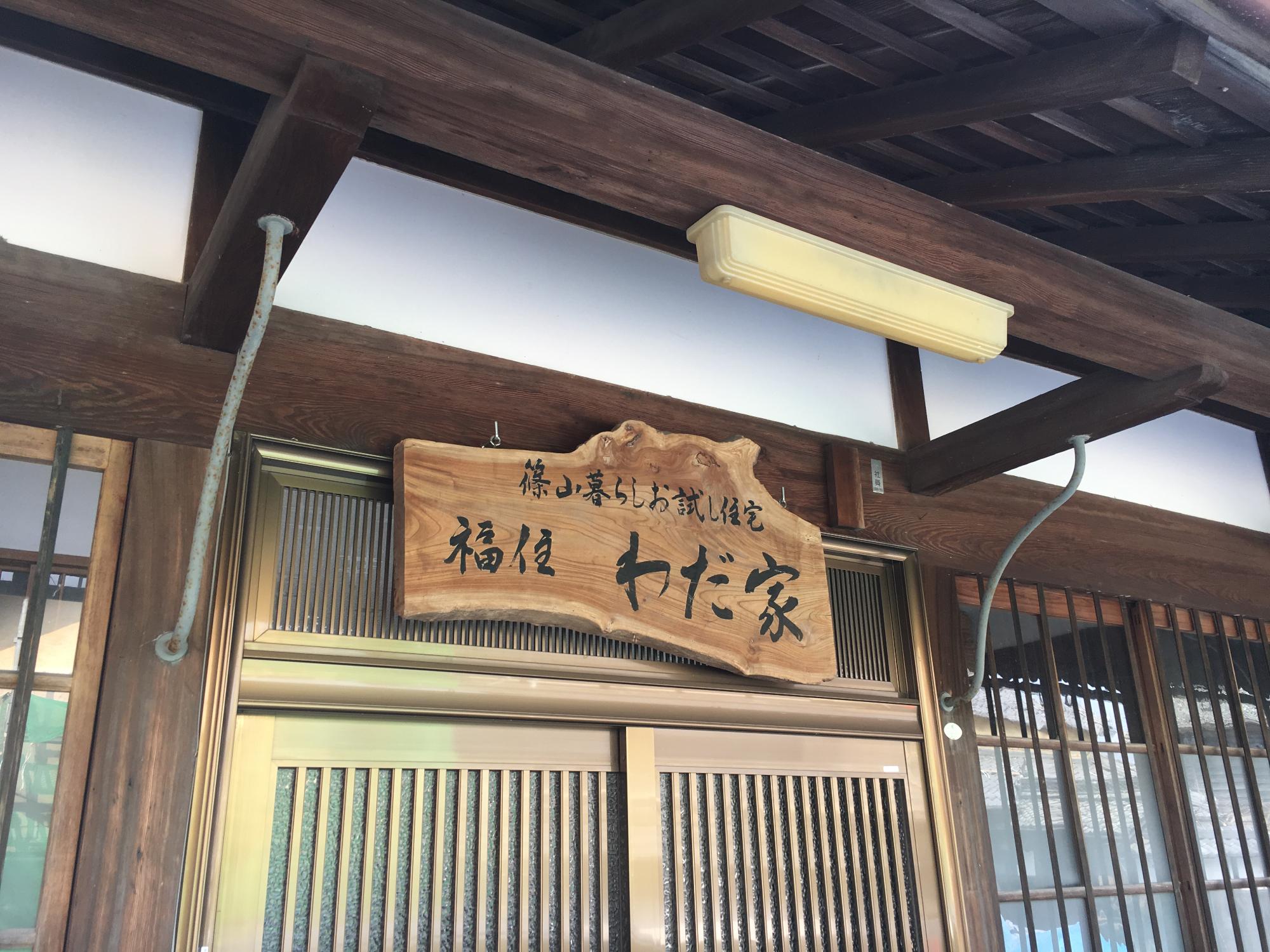 古民家住宅の玄関写真、看板には「篠山暮らしお試し住宅 福住わだ家」と書かれている