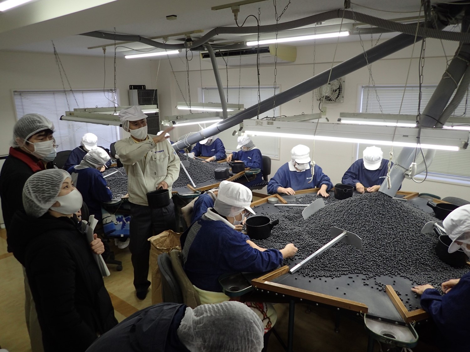 調査員の方が、小田垣商店で黒豆の手選りの見学をされている。