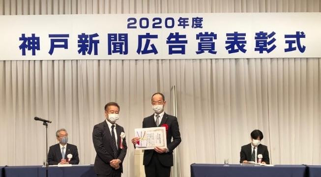 表彰式で、表彰状を手にしている市職員と神戸新聞社の方。
