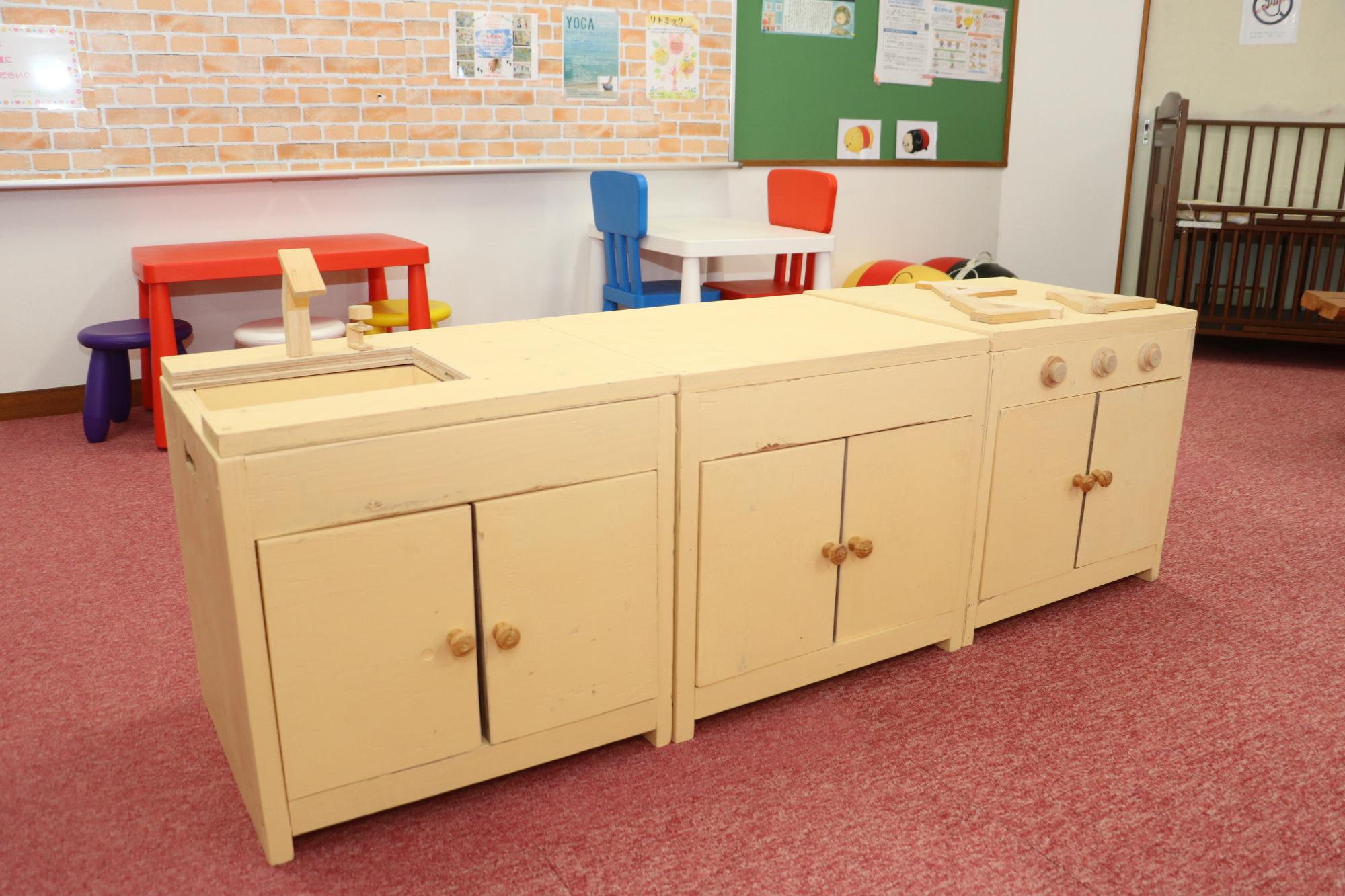 木製のキッチン棚。コンロが3口、真ん中に作業場がある。