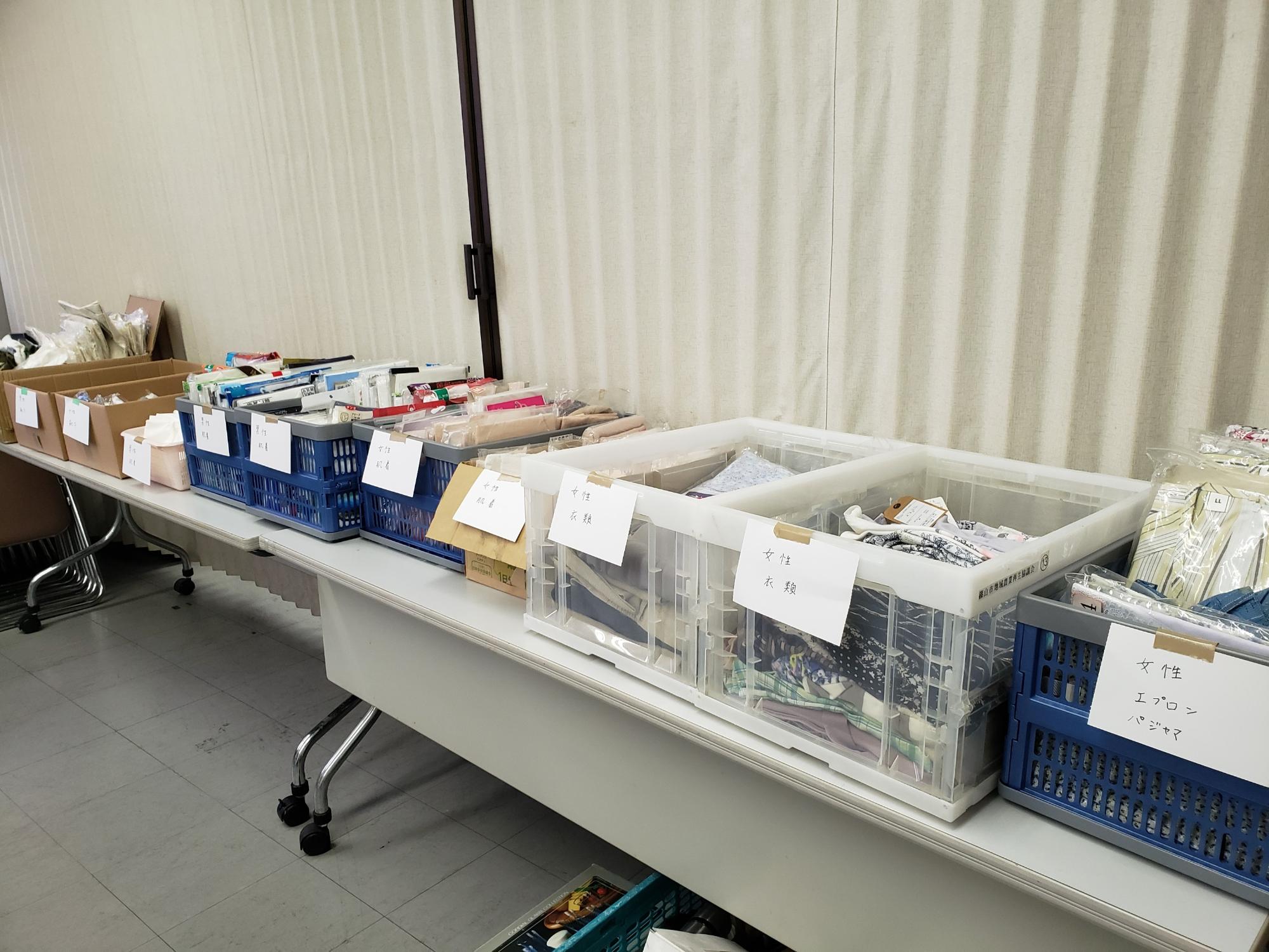 机の上に、コンテナが並べられており、それぞれエプロンや衣類などが入っている