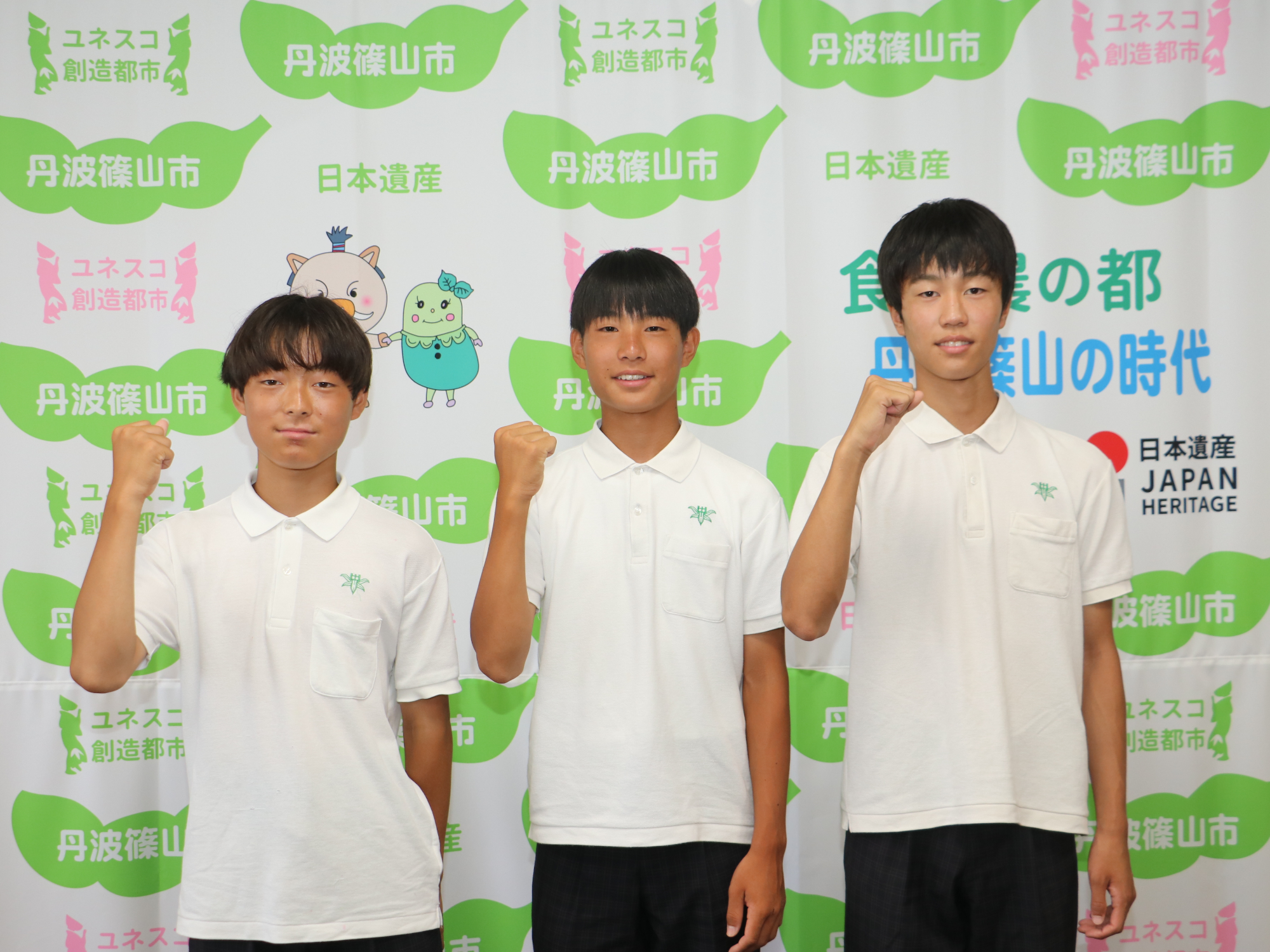 半袖の制服を着た男子中学生3人が右手でガッツポーズをして記念撮影