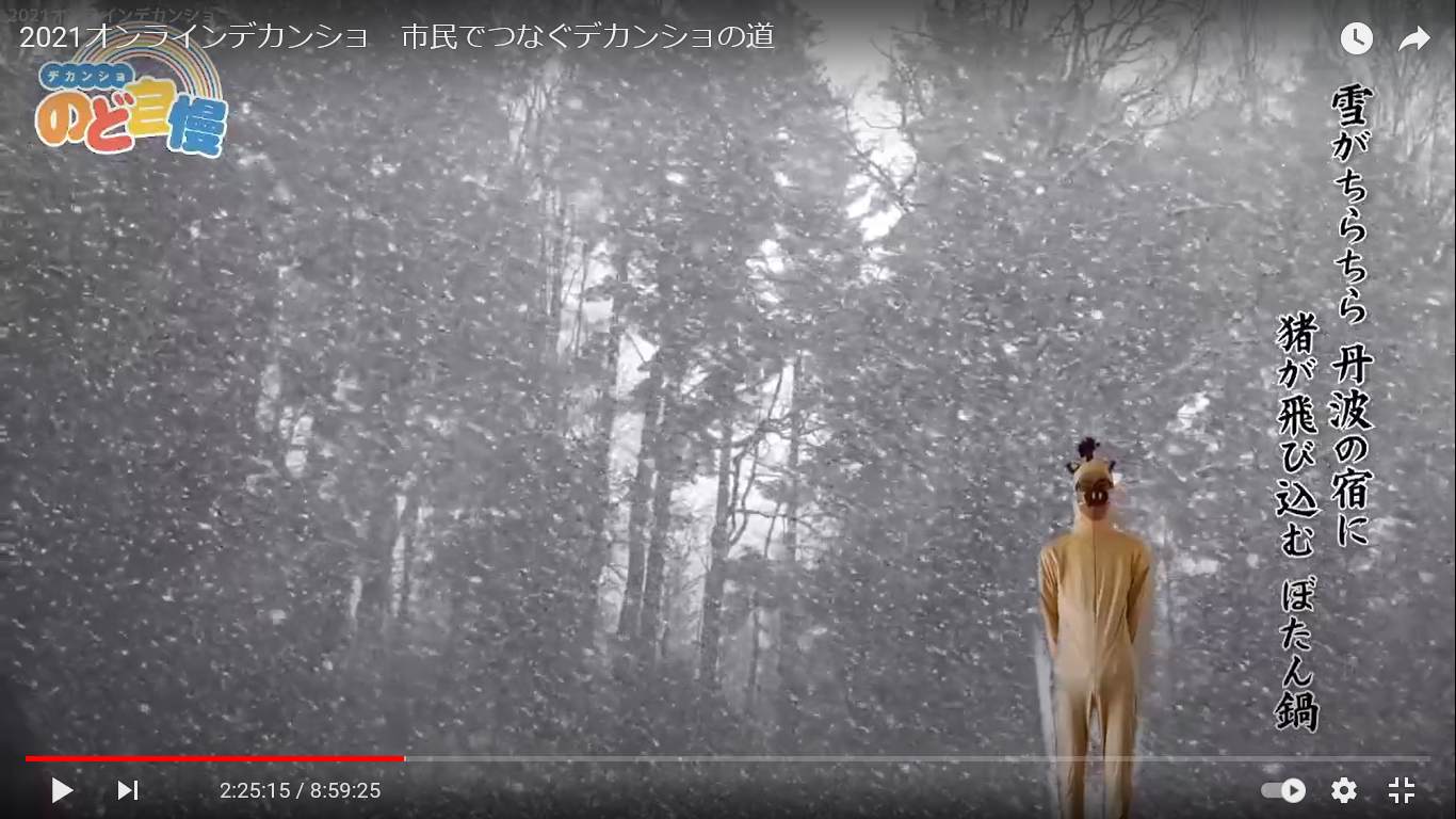 雪景色を背景に猪の着ぐるみを着た男性が立っている