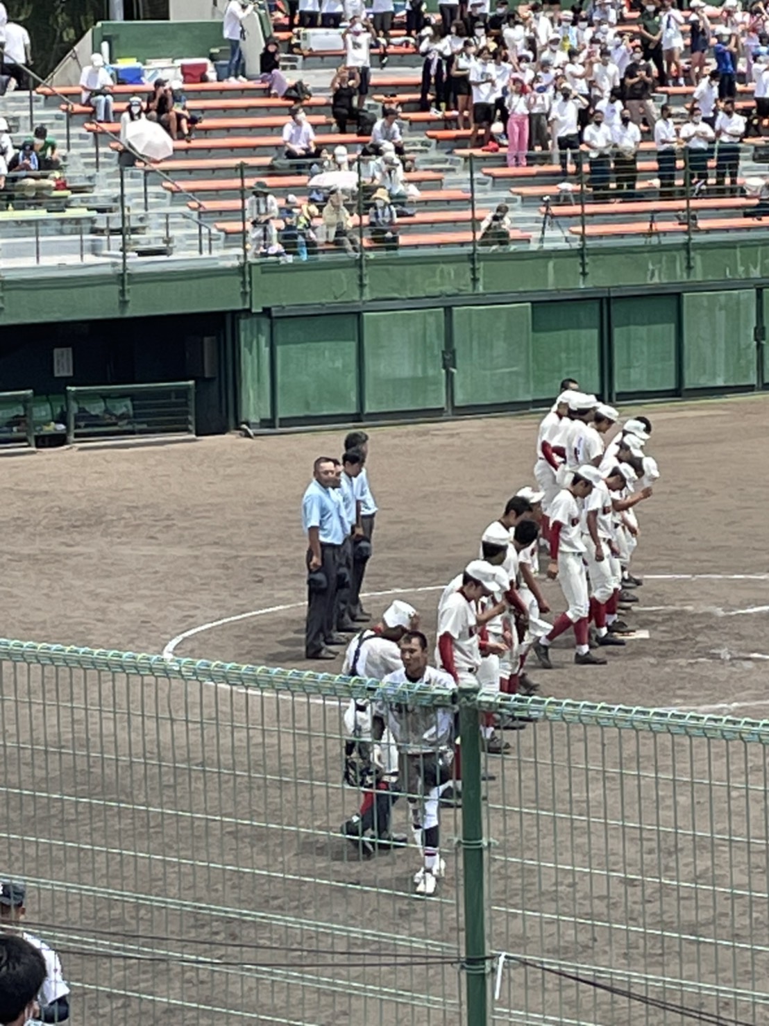 野球の試合後に選手が礼をしている。後ろには審判が並んで立っている。