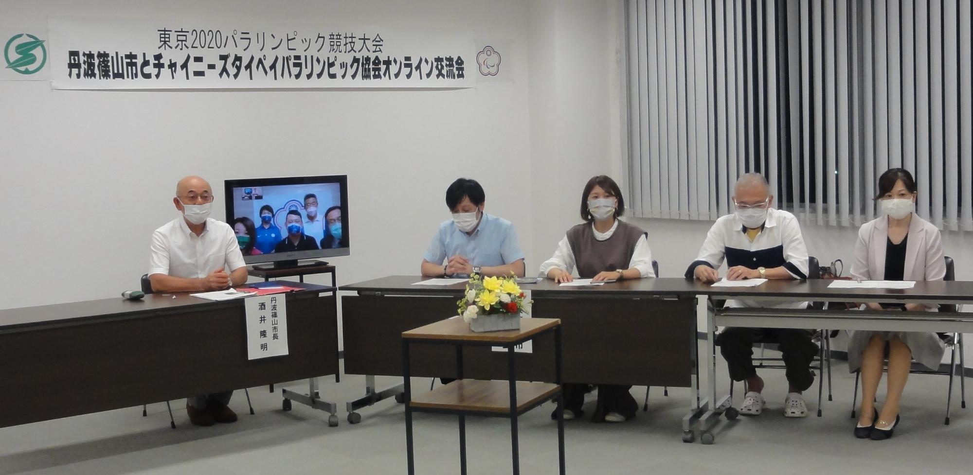 台湾の卓球選手とオンラインでの事後交流をしている。モニターが真ん中にあり、左右に市長や卓球協会の方が座っている。