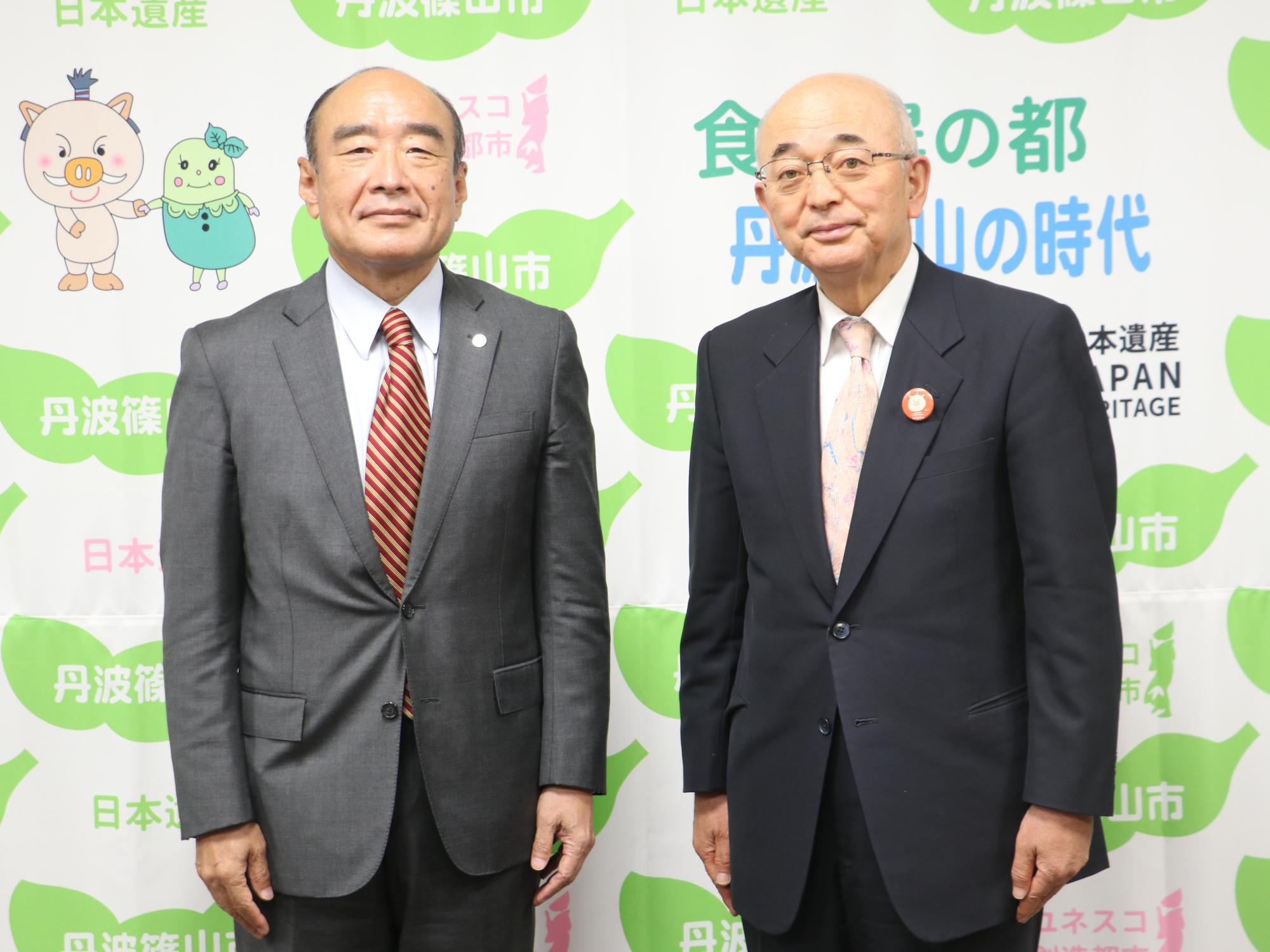 報道用のタペストリーの前で、サンテレビの社長と市長の記念撮影