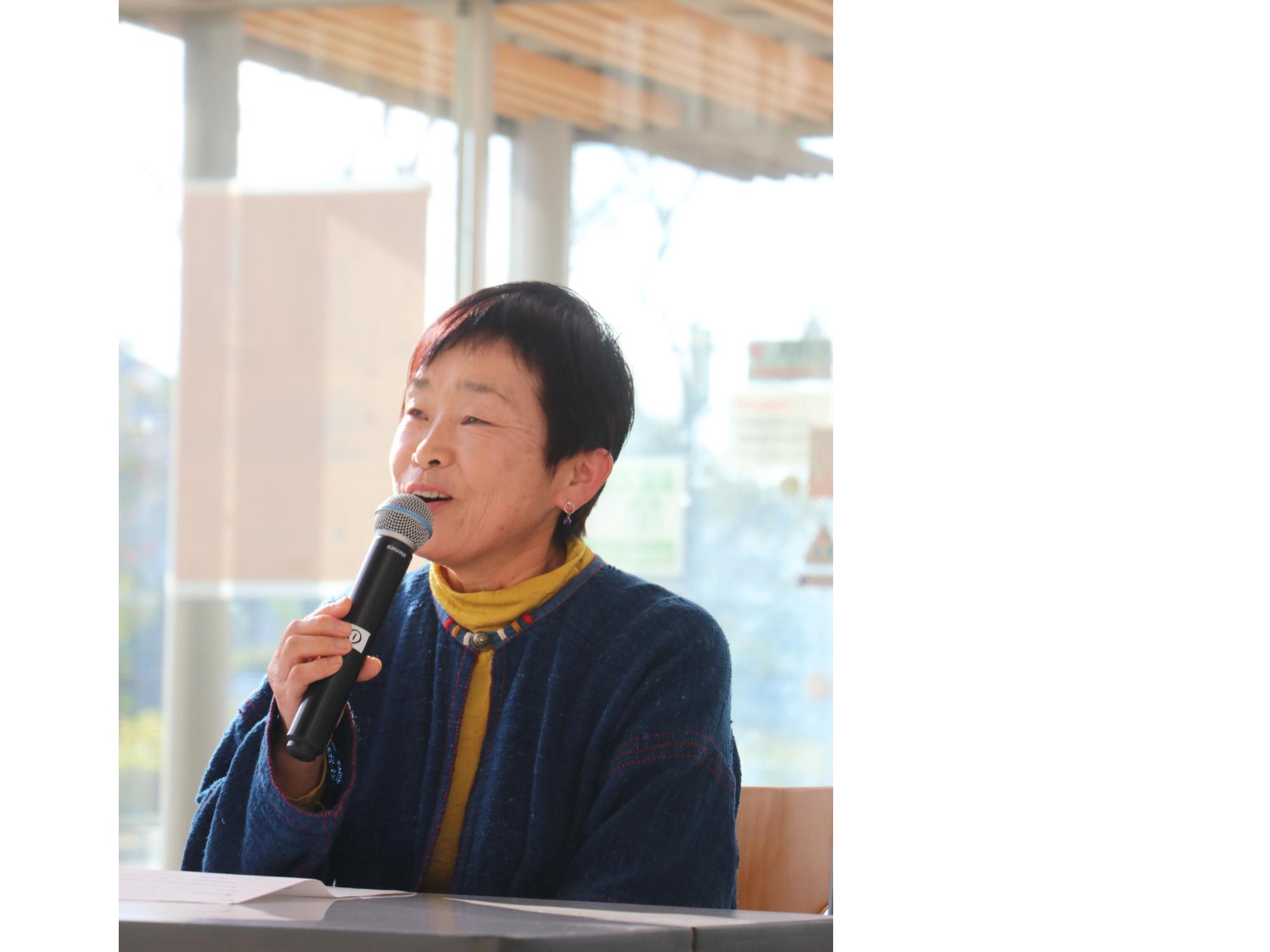 マイクを手に持った女性が話している