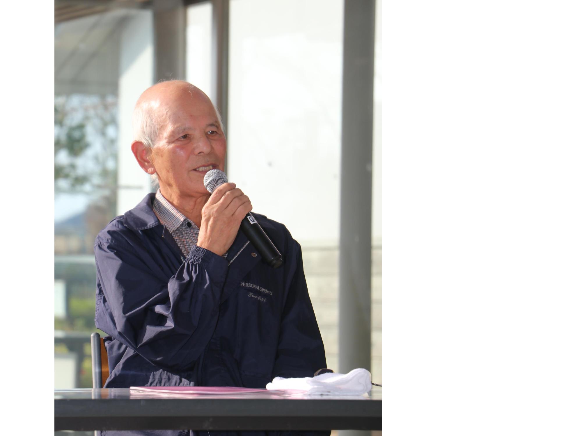 マイクを手に持った男性が話している