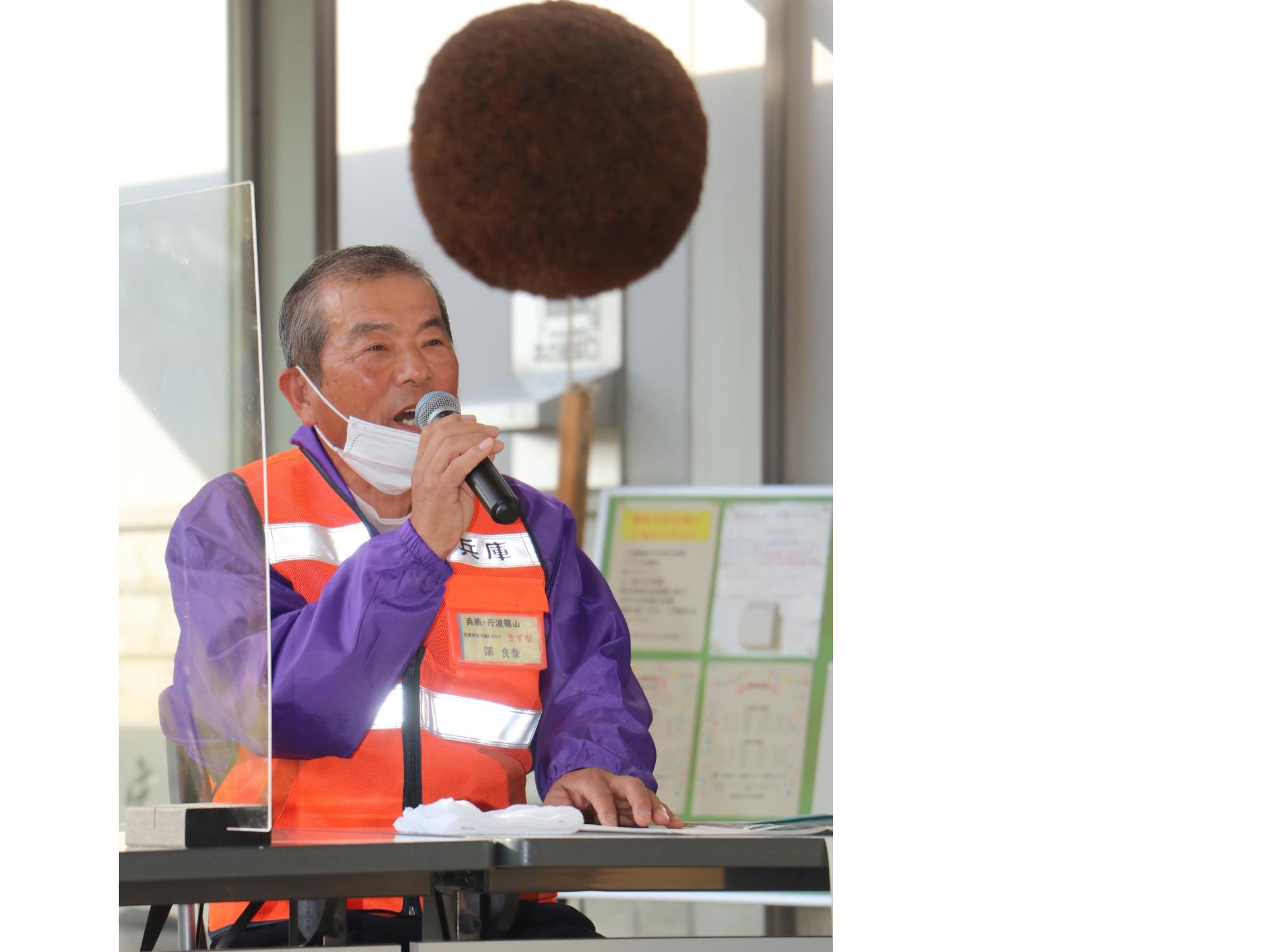 マイクを手に持った男性が話している