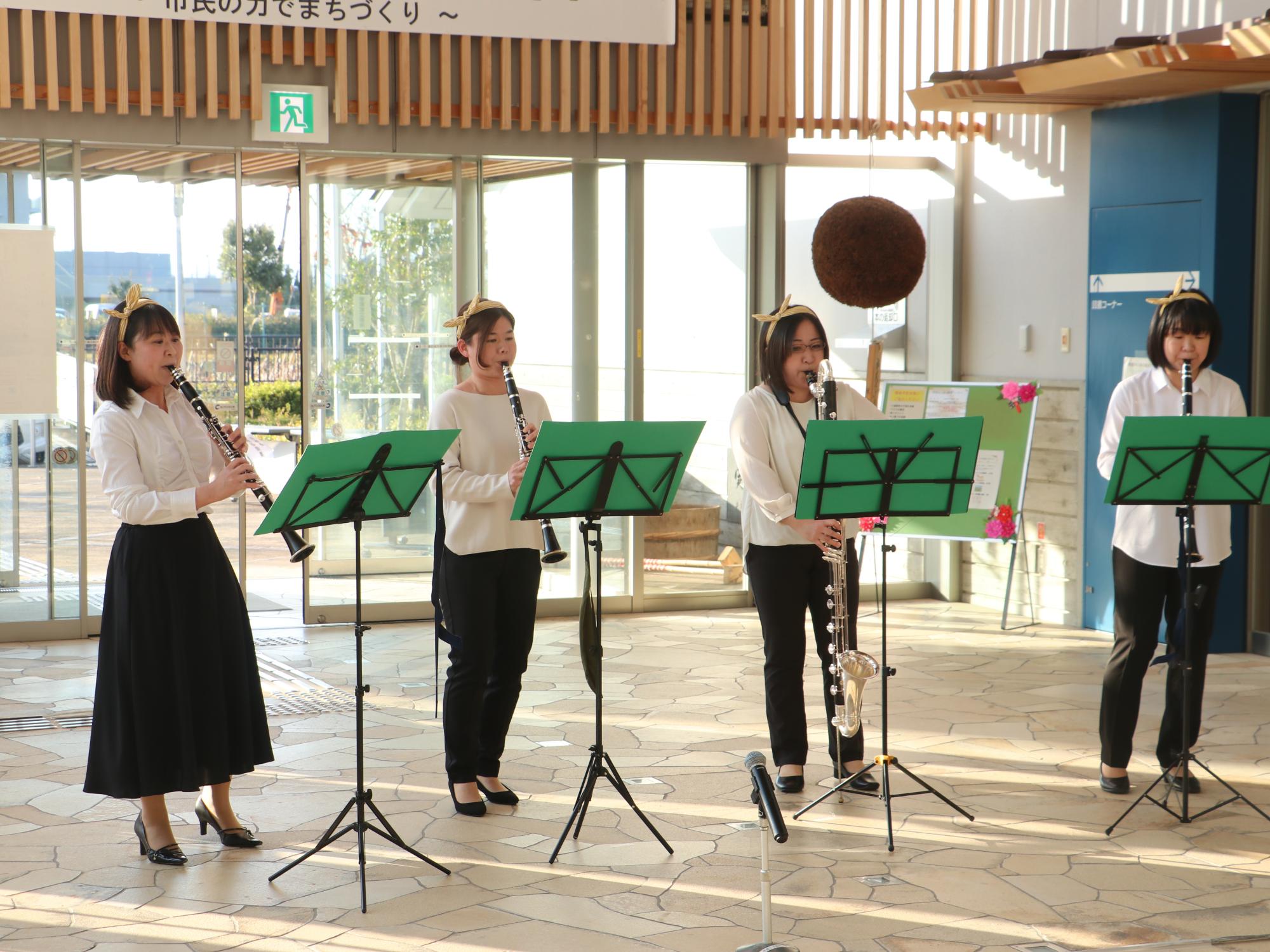 頭に黄色のリボンを結んだ女性たちがクラリネットを演奏している