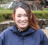 学校の前庭を背景に女性が立っている