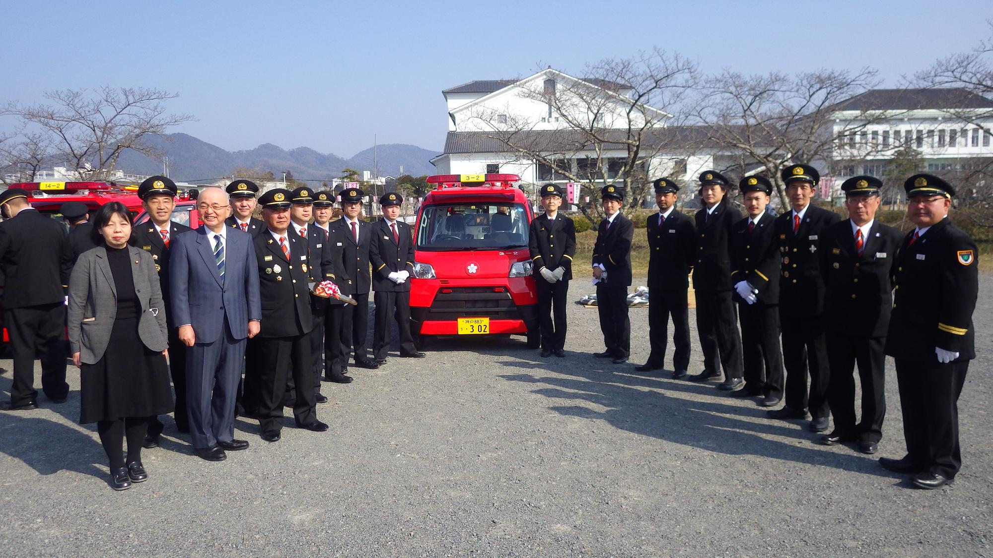 新しい車両の前で、市長と向井議員、消防団の方が並んでいる