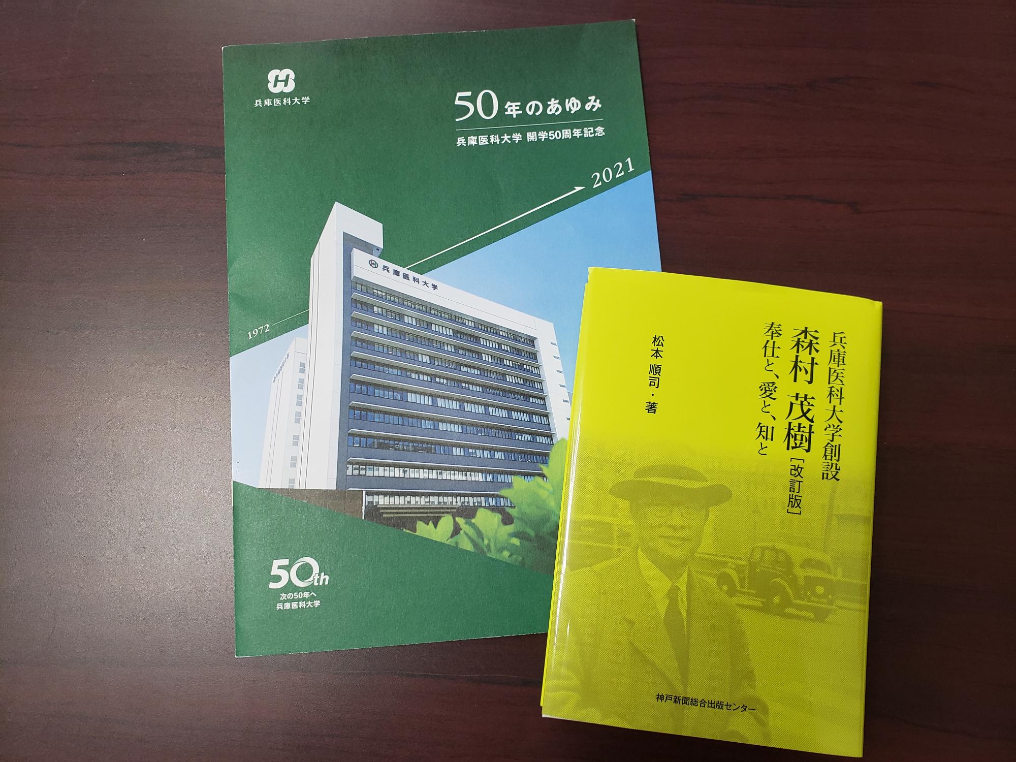 兵庫医科大学の50年のあゆみの冊子と創設者の書籍が机に並べてある