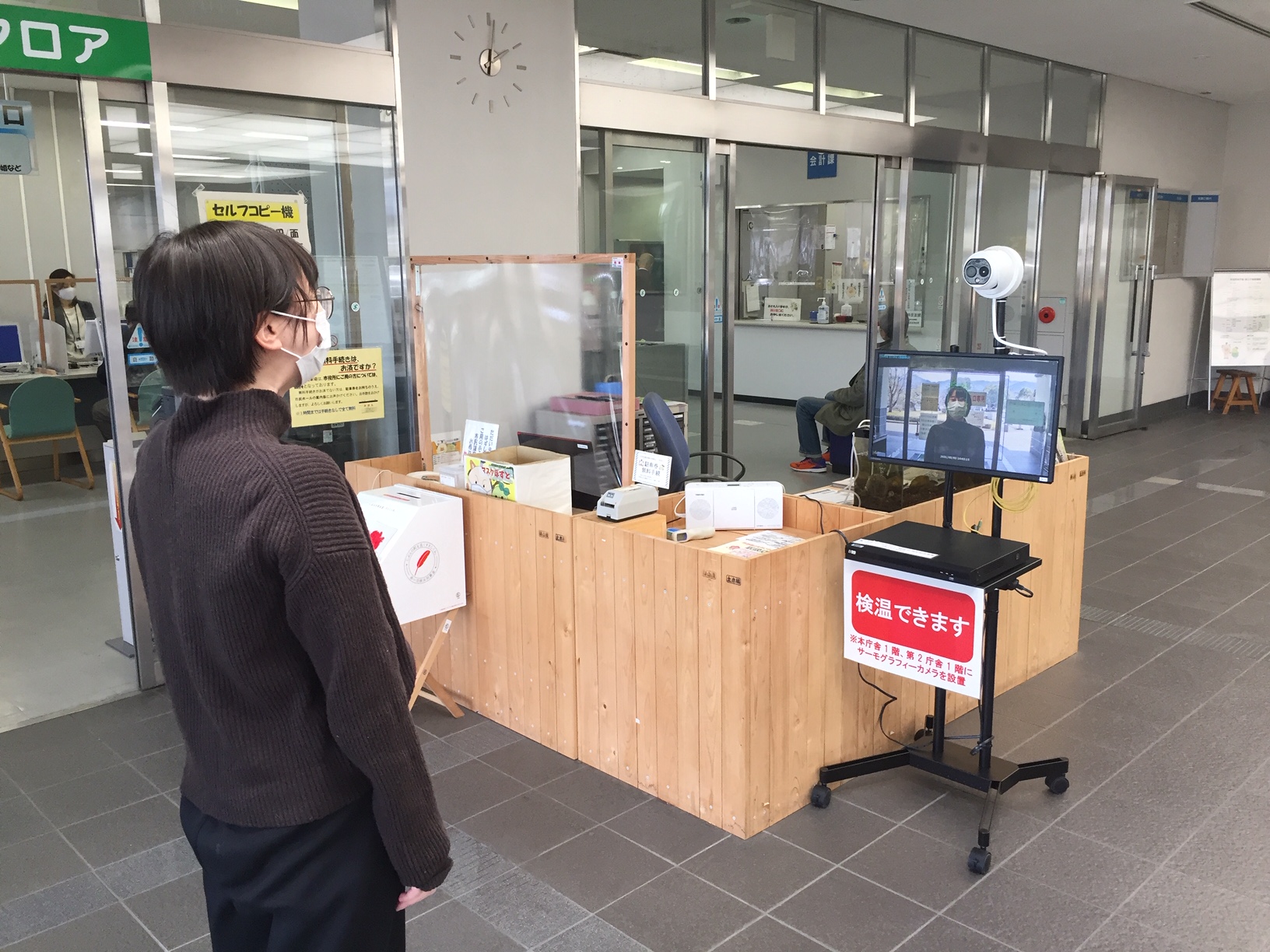 サーモグラフィーカメラの前で体温を検温している女性