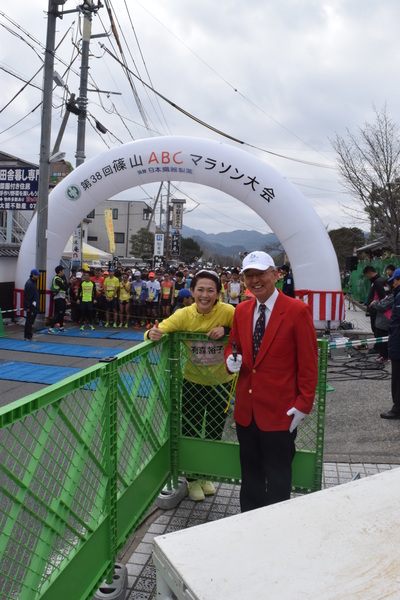 市長が赤のブレザーを着て有森 裕子さんと笑顔で写っている、その後ろにスタート地点に多くのランナーがいる写真