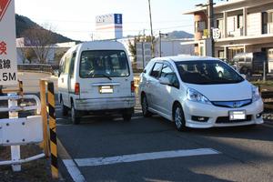 踏み切りで対向車がぎりぎりで通っている写真