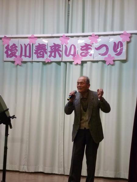 ステージで後川のカラオケクラブの男性が熱唱している写真