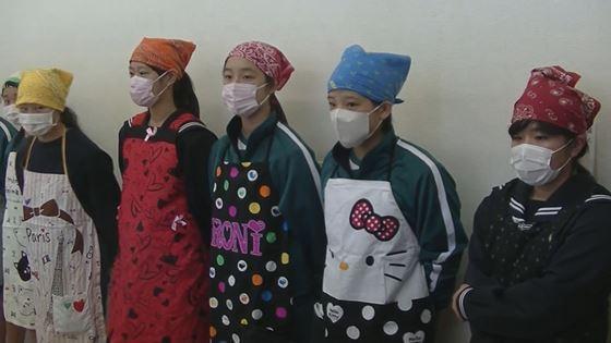 エプロンとマスクをつけた中学生5名が立っている映像写真