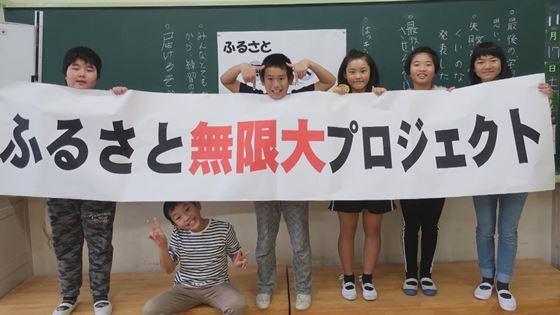 「ふるさと無限大プロジェクト」と書かれた大弾幕を手に小学生男女6名が写っている映像写真