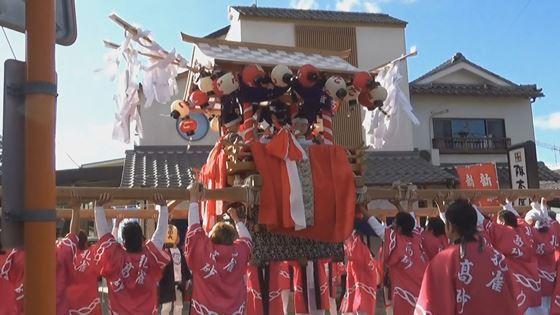 春日神社秋季例祭にて大勢の赤い法被を着た男性たちがお神輿を担いでいる映像写真