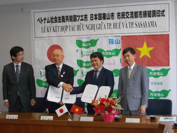 壁には日本とベトナムの国旗が飾られ、市長がベトナムの方と握手をし、記念撮影している写真