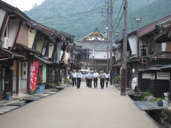 両脇に昔ながらの家が立ち並ぶ職人町を散策している市長と関係者達の写真