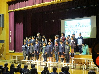 30名ほどの4年生のこどもたちが、合唱をするように横3列に並んでいる写真