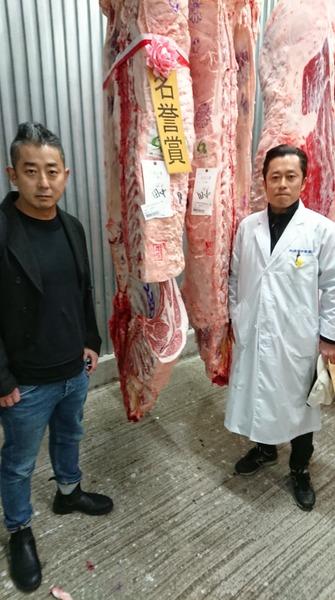名誉賞の枝肉（牛肉の塊）のお肉を間に、白衣を着た田中 久工さん、浜田 寿人さんで記念写真